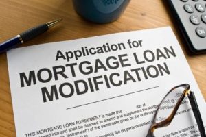 Application for mortgage loan modification form with pen and calculator on desk.