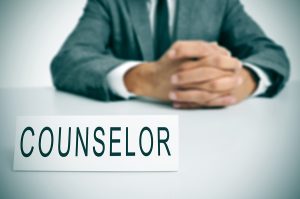Counselor sign on a table in front of a person in a suit.
