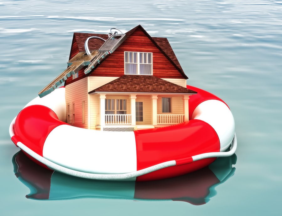 House with a set of keys on top, floating in a life ring on water, symbolizing foreclosure or mortgage relief.