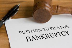 Petition to file for bankruptcy with a gavel and pen on paper.