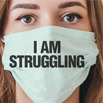 Facing financial hardship with a protective face mask and a sign reading "I am struggling".
