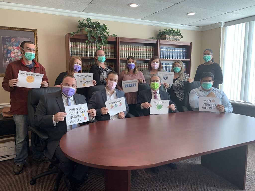 People in masks holding motivational signs in a law office conference room.