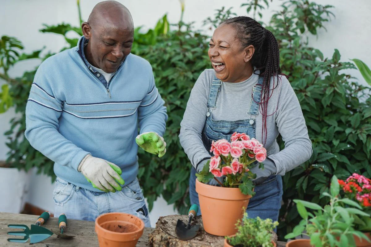 A couple laughing while planting flowers together in a garden