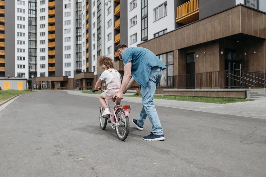 A father teaching his young daughter how to ride a bicycle