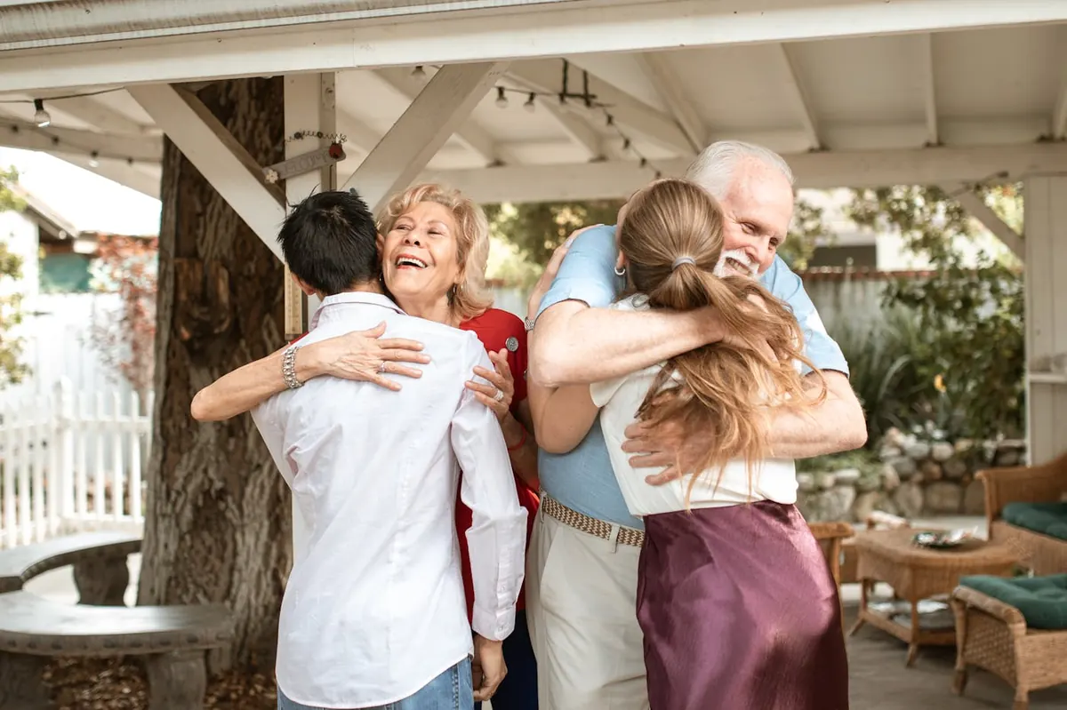 Multi-generational family hugging on a porch